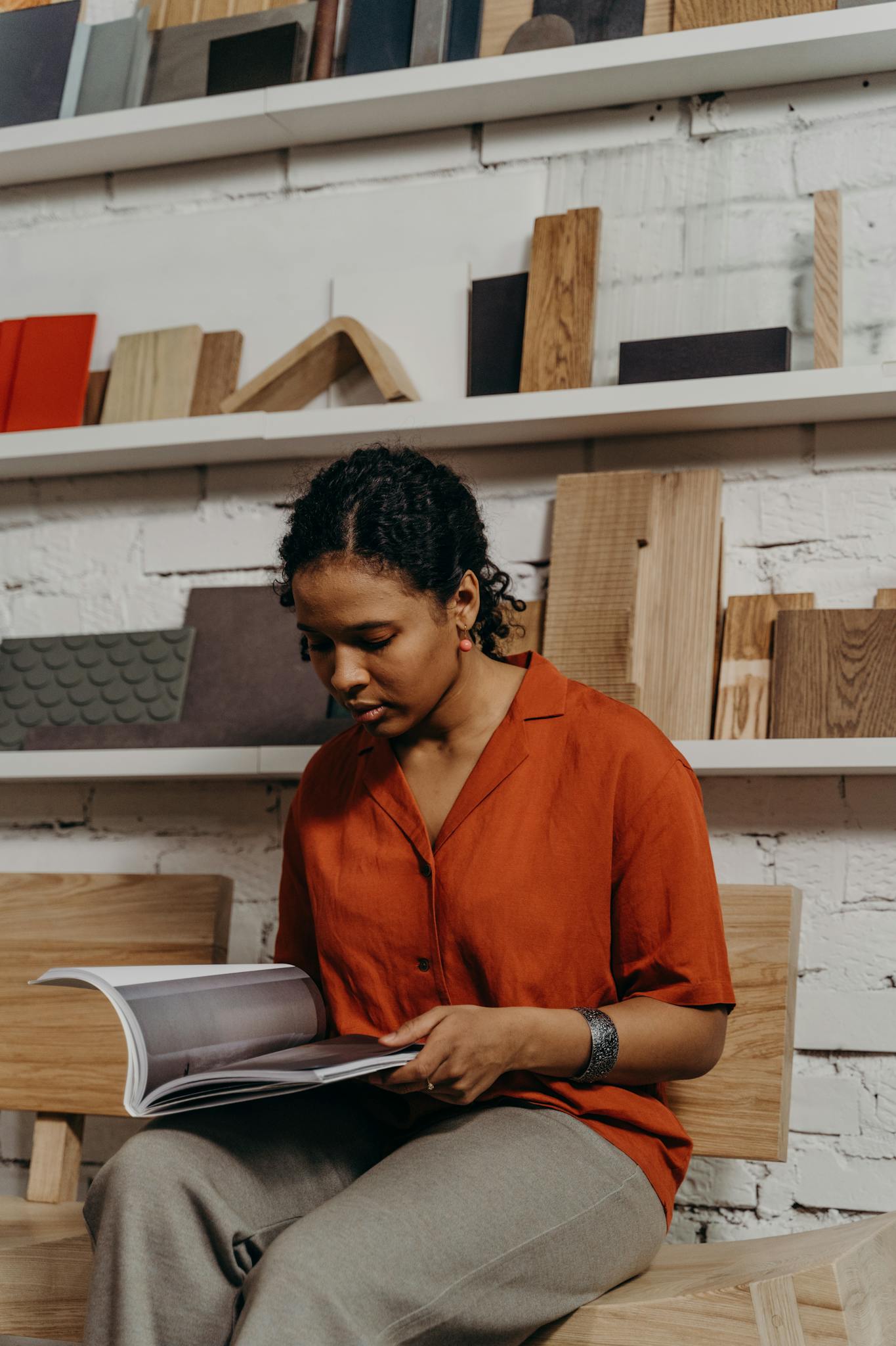Woman exploring design options in a showroom catalog amidst wooden samples.